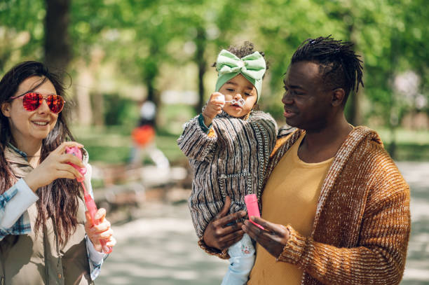 istock Multiracial family blowing soap bubbles in park 1395213906