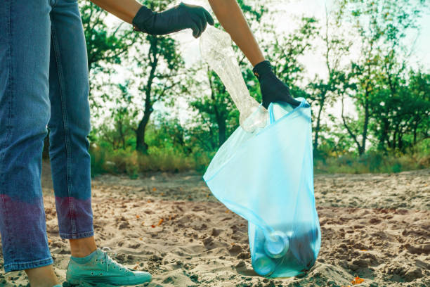 istock Woman puts a plastic bottle in a trash bag 1395213960