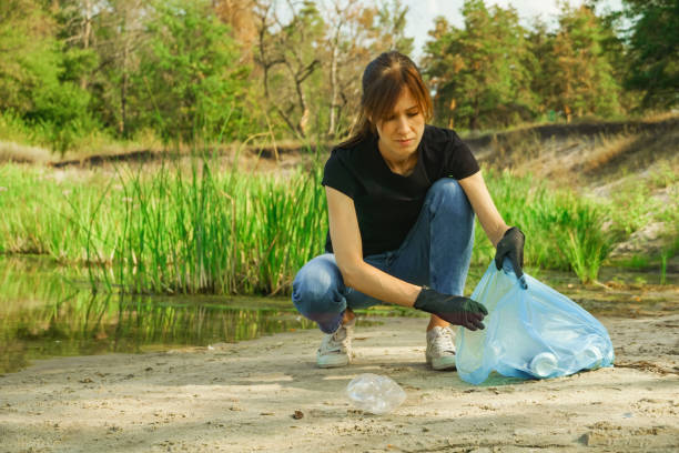 istock Woman collects garbage plastic trash bottle in bag rubbish 1395214077