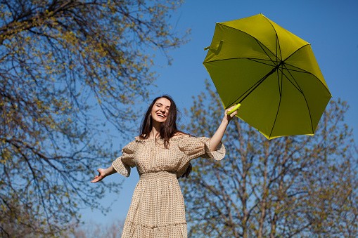 Young woman jumping with green umbrella at the park