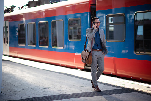 Young businessman on train station talking on phone. And walking in train