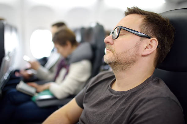 istock Mature man sleeping while traveling by an airplane. Tired passenger napping during flying in aircraft. 1395225942