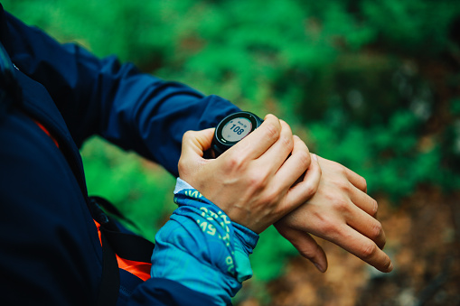 Female trail runner checking her smart watch in the forest.