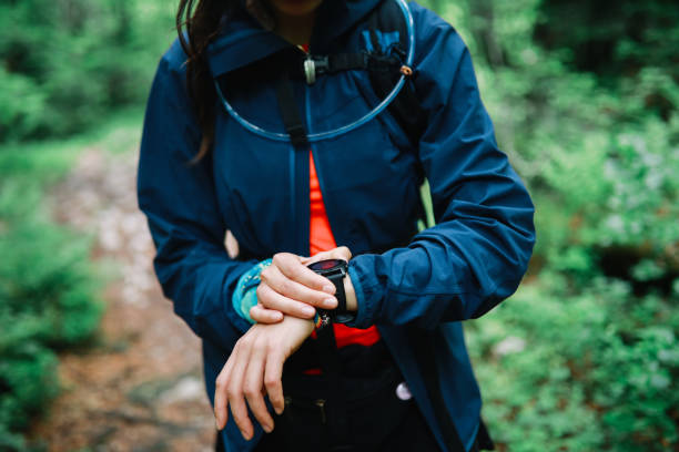 trailrunnerin überprüft ihre smartwatch im wald - checking the time watch women looking stock-fotos und bilder