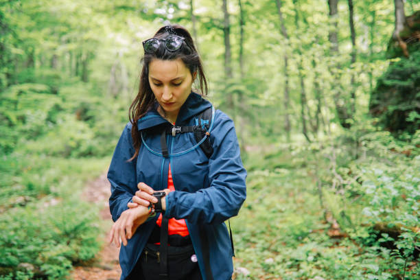 trailrunnerin überprüft ihre smartwatch im wald - checking the time watch women looking stock-fotos und bilder