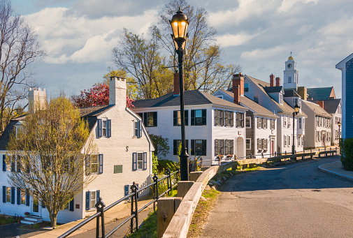 Plymouth, Massachusetts, USA- May  1, 2022- Afternoon sunlight illuminates the fronts of several old classic homes on Leyden Street in Plymouth, Massachusetts.  The first home on the left was the site of the very first house built by the Pilgrims in 1620.