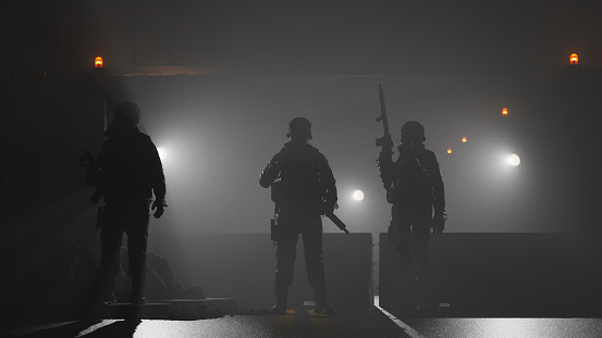 Armed forces guarding a barricaded road at night