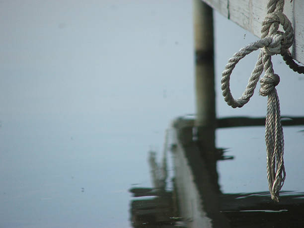 Tie a Knot Knotted rope, hanging above the water from a wooden boat dock bollard pier water lake stock pictures, royalty-free photos & images