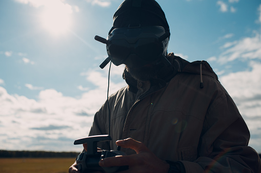 Moscow, RUSSIA - September 18, 2021: Man controlling fpv quadcopter drone for aerial photography and videography with goggles antenna remote controller.