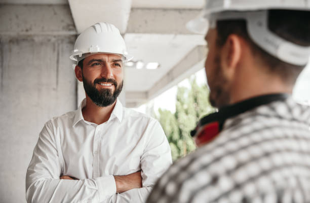 istock Smiling foreman and builder in hardhats at construction site 1395253542