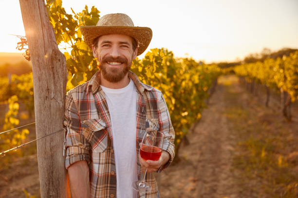 istock Cheerful farmer with wine resting on vineyard 1395253632