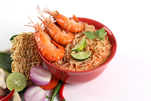 Instant noodles spicy tom Yum kung. Tom Yum kung in a red bowl with ingredients placed on a white background have copy space.