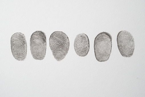 different black fingerprints on a paper close up