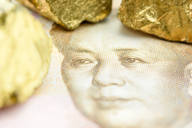 концепция инвестиций в драгоценные металлы и валюту: железная руда золотого цвета на деньгах китайского юаня, изображающая инвестирование - finance china stock exchange shenzhen стоковые фото и изображения