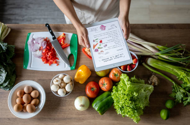 close-up on a woman cooking at home following an online recipe - yemek kitapları stok fotoğraflar ve resimler