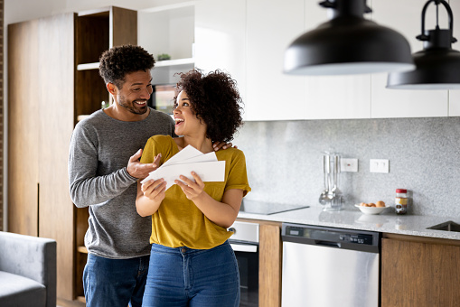 Portrait of a happy couple reading a letter in the mail and looking very excited â good news concepts