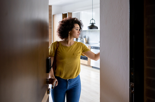 Latin American woman at the door of her house activating the alarm before leaving â domestic life concepts