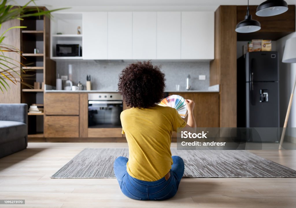 Woman at home choosing a color to paint the walls Casual woman at home choosing a color to paint the walls from a color swatch - home decor concepts Kitchen Stock Photo