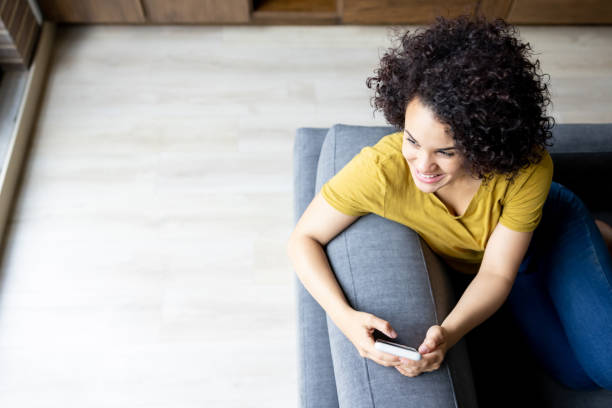 istock Happy woman using her phone while relaxing at home 1395273200
