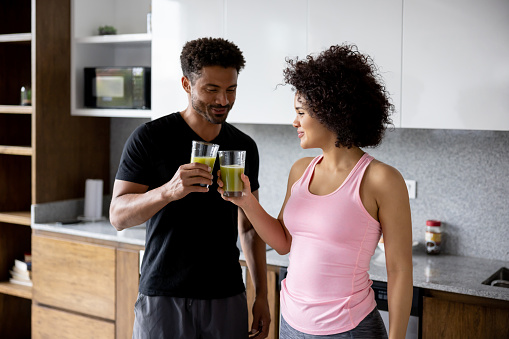Healthy eating couple at home making a toast with a green juice - healthy eating concepts