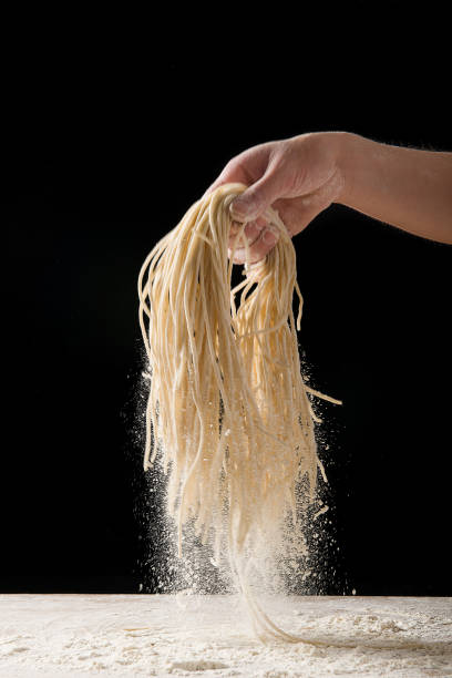 istock Hand holding noodle on black background 1395273927