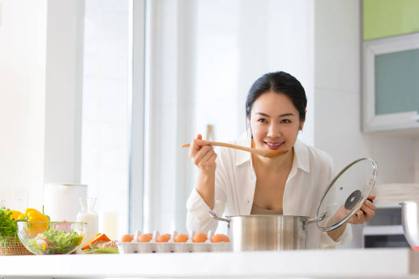 Young housewife tasting food in the kitchen - stock photo stock photo