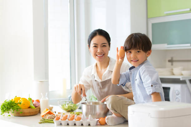 Family kitchen parentage. A young mother taught her son to break eggs for baking. - stock photo stock photo