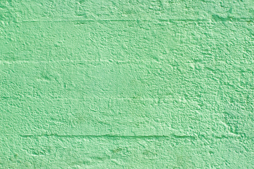 Concrete bricks wall painted green, blocks pattern, rough texture, full frame image suitable for backgrounds purposes.