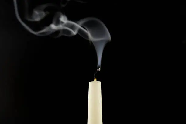 Photo of White candle extinguished on black background