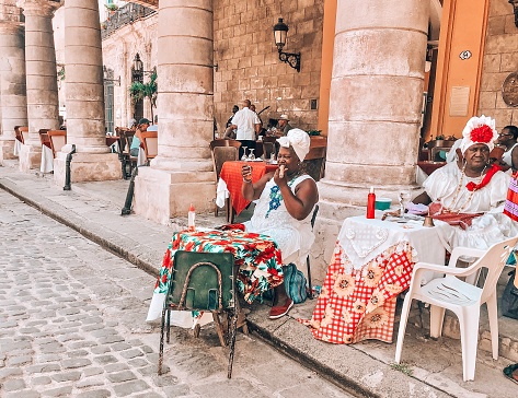 Cuban ladies in traditional dresses sitting in front of Cathedral of Havana, Cuba
