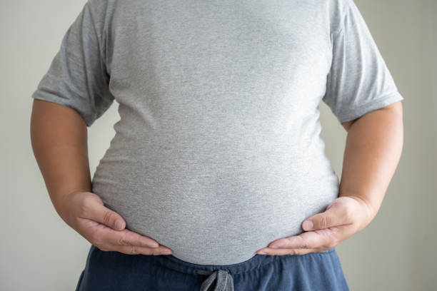 Big fat man standing to show real size with causual clothing. Big fat man standing to show real size with causual clothing. Concept of unhealthy body need to figure out. pot belly stock pictures, royalty-free photos & images