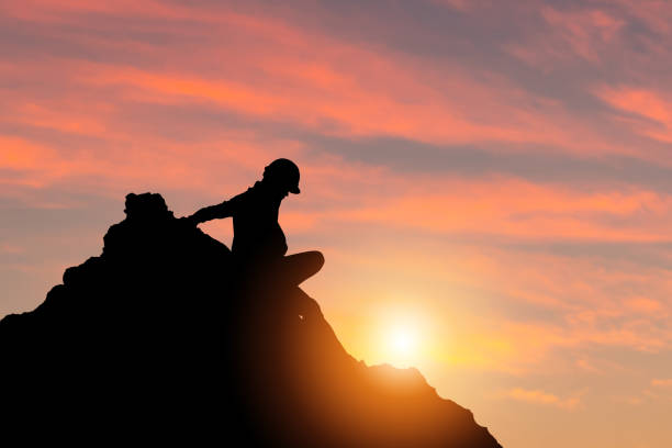 istock Silhouette of engineer man in hard hat on a mountain top sunset sky background 1395282912