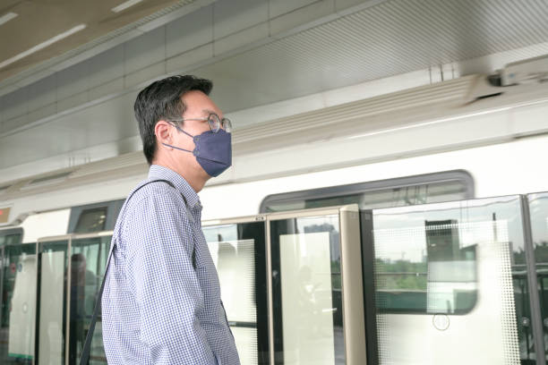 istock Businessman with face mask on standing on subway platform waiting for train. 1395283027
