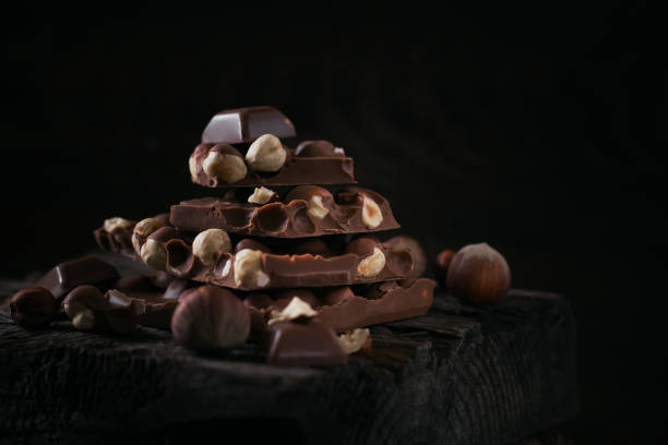 istock Pile of hazelnut milk chocolate and nuts on dark background 1395283922