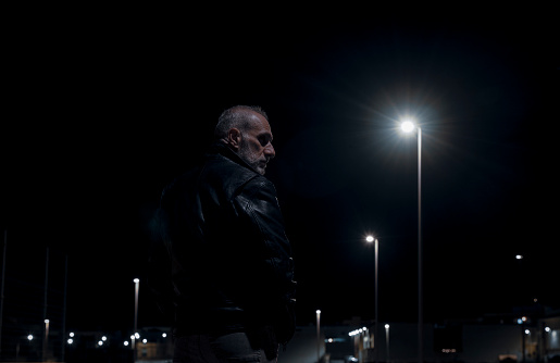 Adult man on street at night with lights of street lamps