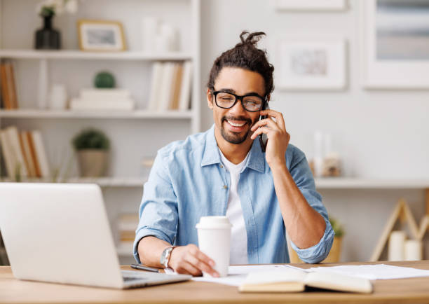 istock Positive black freelancer talking on smartphone at home 1395291818