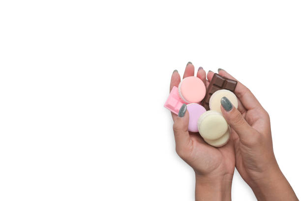 Hands holding colorful pastel macaroons isolated on white background.
