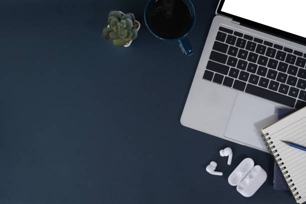 istock Computer laptop, cup of coffee, notebook and wireless earphone on dark blue background. Flat lay. 1395292982