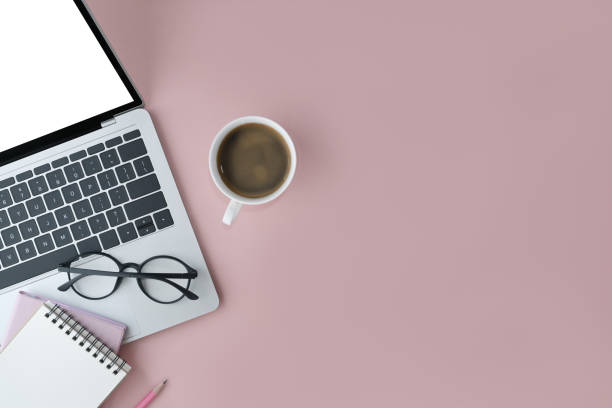 istock Above view laptop computer, eyeglasses, coffee cup and notepad on pink background with copy space. 1395292986