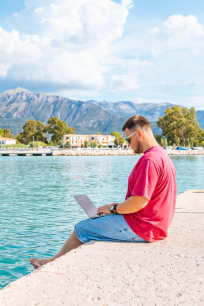 istock man freelancer working on laptop at city harbor bench 1395294023