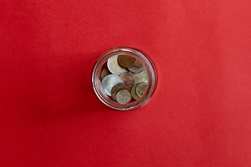 Glass jar with coins with red background