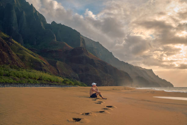 istock Man watching the sunset at Kalalau Beach, Hawaii 1395295143