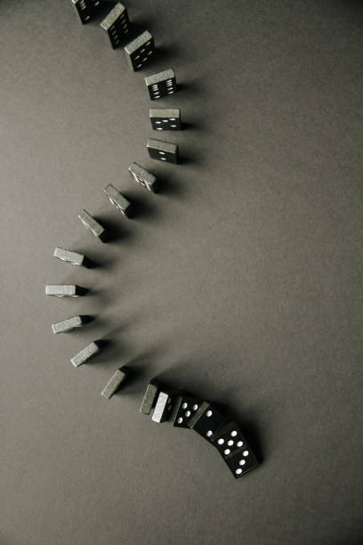istock Black dominoes chain on dark table background 1395296033