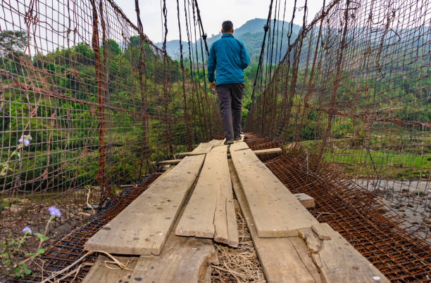 istock man sitting alone at vintage iron suspension bridge from low angle 1395296178