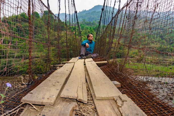 istock man sitting alone at vintage iron suspension bridge from low angle 1395296268