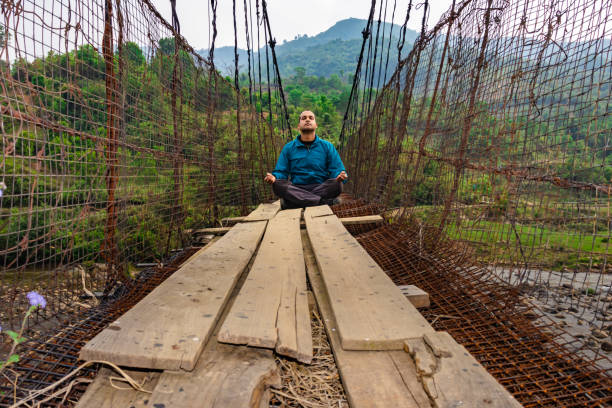 istock man meditating at vintage iron suspension bridge from low angle 1395296270