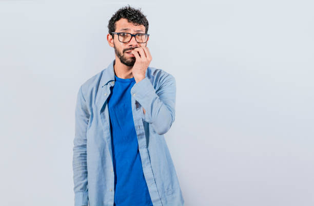 istock Guy with worried expression on isolated background, Nervous young male with worried expression, bites nails and looks anxiously. Nervous man concept 1395297317