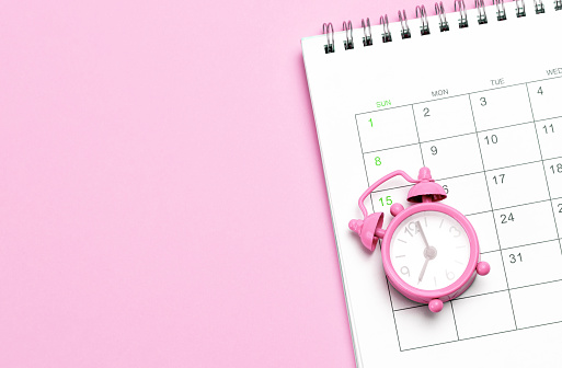 Despertador rosa y calendario sobre fondo rosa. Concepto días de menstruación o menopausia. Plantilla Copiar espacio para texto. maqueta photo