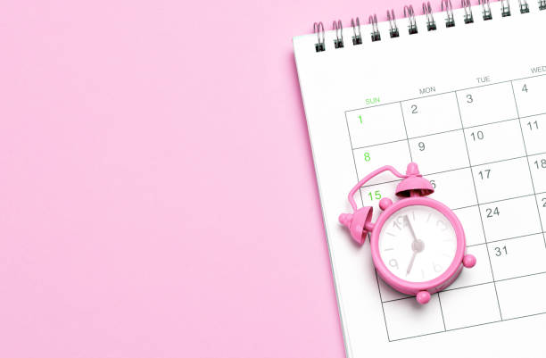 pink alarm clock and calendar on a pink background. concept days of menstruation or menopause. template copy space for text. mock-up - ovulação imagens e fotografias de stock