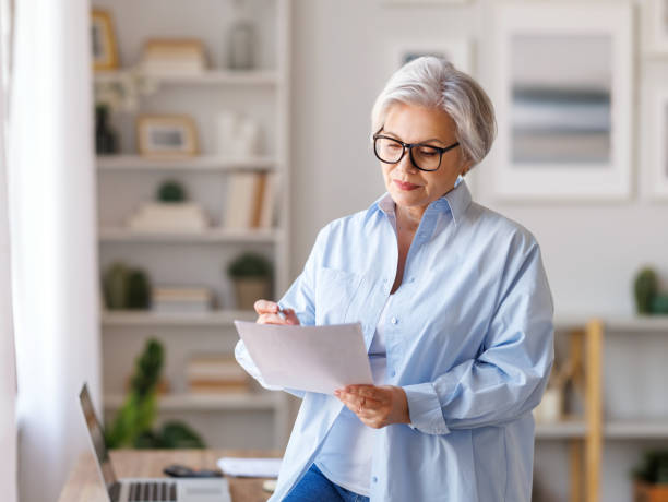 istock Mature businesswoman working at laptop, reading documents and take notes in home office 1395297701